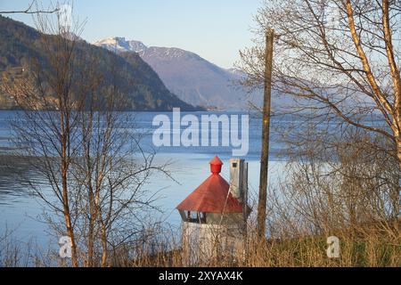 Nordfjord in Norvegia. Vista sulle montagne innevate. In primo piano un piccolo faro. Deserto in Scandinavia, al sole. Orizzontale phot Foto Stock