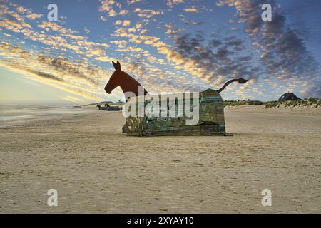 Sulla spiaggia di Blavand, Danimarca, guardando un bunker con testa di cavallo. Tramonto all'orizzonte Foto Stock