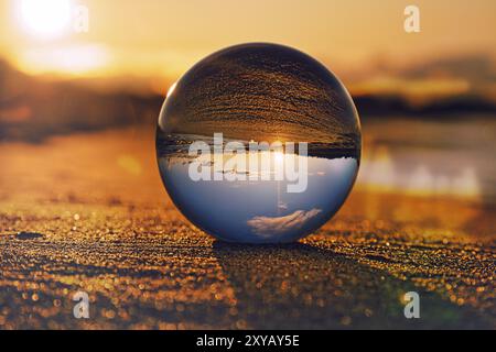 Globo di vetro sulla spiaggia del Mar Baltico in Zingst in cui è raffigurato il paesaggio. Il tramonto crea un'atmosfera calda e luminosa Foto Stock