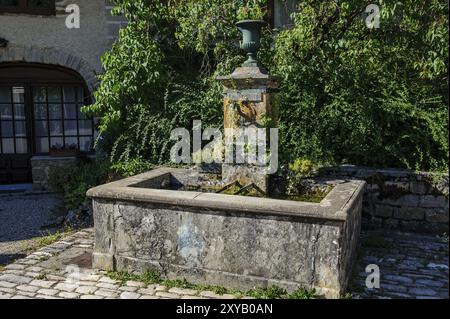 Vecchia fontana storica con rubinetto curvo beccuccio dell'acqua per una fornitura permanente di acqua potabile acqua potabile pulita per il consumo umano cibo con cartello Eau p Foto Stock