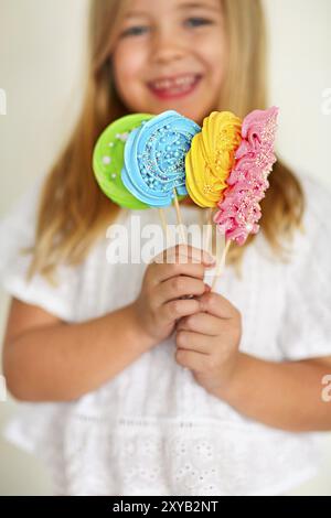 Carino bambina con caramelle pop su sfondo bianco Foto Stock