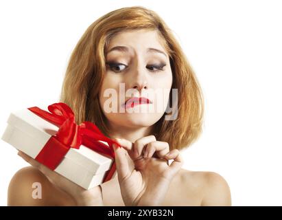 Bella giovane bruna che apre un regalo decorato con nastro rosso Foto Stock