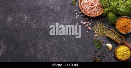 Spezie ed erbe su fondo di pietra nera. Vista dall'alto con spazio libero per menu o ricette Foto Stock