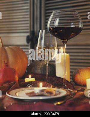 Ambientazione autunnale. Cena del Ringraziamento. Frutta di stagione autunnale, zucche, piatti, vino e candele Foto Stock