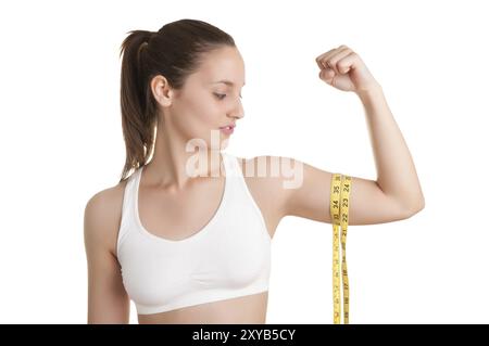 Potente donna misurando il suo bicipite con un giallo nastro di misurazione Foto Stock