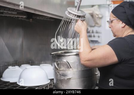 Dipendente donna che carica le casseruole in una lavastoviglie industriale del ristorante Foto Stock