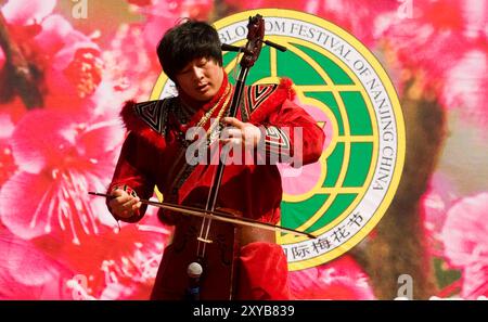 Musicista mongolo che suona il morin khuur, uno strumento a due corde durante il Blossom festival a Nanchino, in Cina. Foto Stock