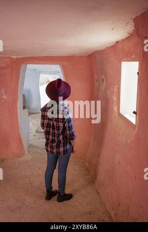 Donna che guarda la finestra all'interno delle grotte di Argueda con pareti rosa, in Spagna Foto Stock