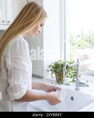 Donna facendo il lavaggio fino in cucina Foto Stock