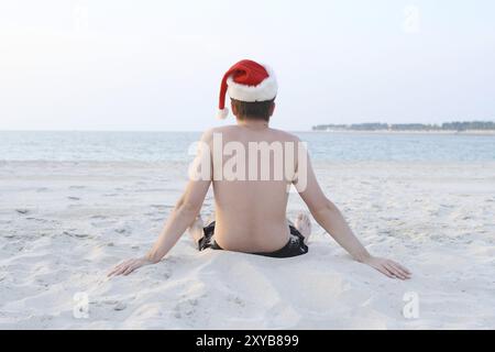 Uomo seduto su una spiaggia e che guarda l'oceano Foto Stock