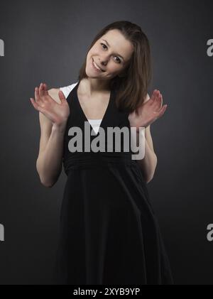 Divertente sorridere giovane ragazza su sfondo scuro Foto Stock