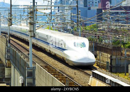 Avvicinando il treno ad alta velocità come a forma di proiettile su alta rotaie elevate circondato da fili visto da sopra vista aerea. Posizione orizzontale Foto Stock