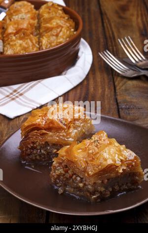 In casa il baklava con noci e sciroppo di miele sul vecchio rustico tavolo in legno Foto Stock