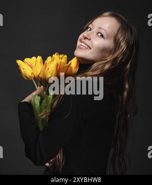 Donna bionda felice con bouquet di tulipani arancioni Foto Stock