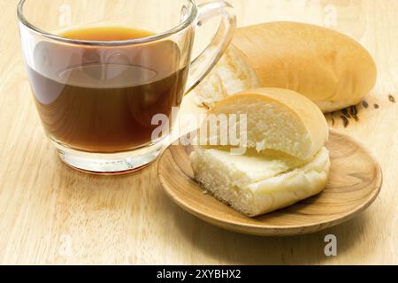 Hotdog pane farcito con aggiunta di zuccheri o di altri dolcificanti burro di crema e una tazza di caffè sulla tavola di legno Foto Stock