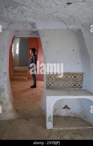 Donna all'interno di Argueda ha abbandonato le grotte che guardano attraverso la finestra con pareti rosa e bianche, in Spagna Foto Stock