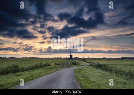 Pista ciclabile per raggiungere il mulino a vento all'alba in estate, Olanda Foto Stock