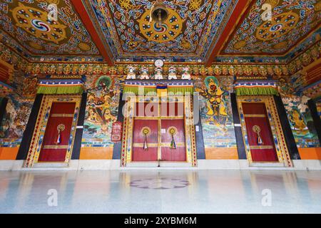Una vista ad angolo basso delle porte e del soffitto splendidamente dipinti dell'ingresso al monastero di Rumtek, sede del Karmapa situato a Gangtok, Sikkim, Foto Stock