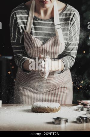 Buon Natale, Felice Anno Nuovo. Cottura del pan di zenzero, torta, cottura dello strudel. La donna in grembiule sta preparando dei biscotti. Schiaffo palme, spruzzi di farina o Foto Stock