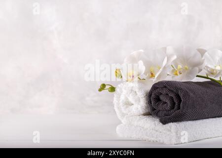 Massaggio Spa e wellness grigio bianco asciugamani e orchidee sulla pietra grea sfondo spazio di copia Foto Stock