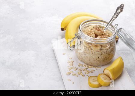 Sana colazione con vecchio stile di avena, miele e banana in un vaso su bianco tavolo in legno Foto Stock