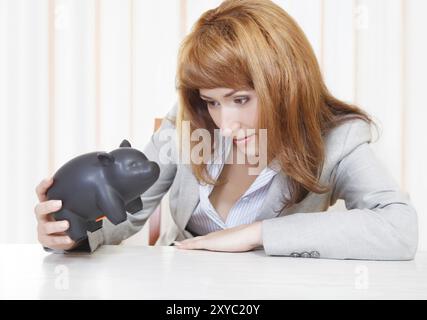 Triste donna d'affari che guarda il salvadanaio Foto Stock