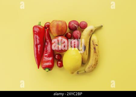 Cibo sano e organico flay concetto su sfondo giallo. Un quadrato fatto di verdure e frutta differenti come limone, mele, banane, sudore rosso Foto Stock