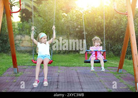 Bambini che giocano su parco giochi nel parco. Due piccole sorelle sul distributore rotazione Foto Stock