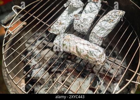 Foglio di alluminio avvolto intorno al formaggio grigliato su una griglia per grigliate primo piano per barbecue Foto Stock
