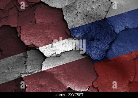 Bandiere della Lettonia e della Russia dipinte su un muro incrinato Foto Stock
