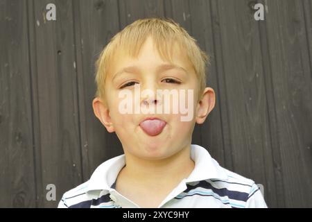 Il ragazzo biondo si allungò la lingua Foto Stock