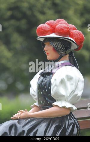 Bambola in costume tradizionale da donna con Bollenhut sulla panchina, Foresta Nera, Bollenhut, abbigliamento, gonna, tradizione, tradizionale, seduta, scultura, flo Foto Stock