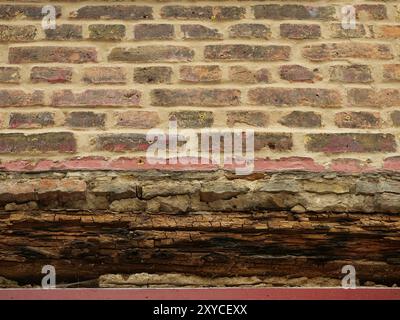 Muratura esposta con architrave in legno decaduto sopra un'apertura della finestra durante i lavori di ristrutturazione. Ideale come trama o sfondo per progetti creativi. Foto Stock
