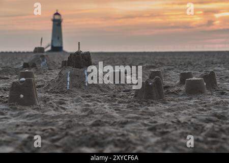 Il Sandcastles On la spiaggia, con serata nuvole e punto di Ayr il faro in background, vicino Talacre, Flintshire, Wales, Regno Unito Foto Stock