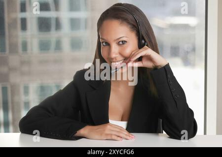 Corporate Donna che parla oltre il suo auricolare in un ufficio Foto Stock