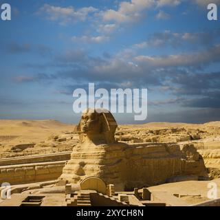 Testa a piedi per tutta la lunghezza e profilo della grande Sfinge presso le grandi Piramidi egiziane in un giorno di cielo blu a Giza, il Cairo, in Egitto. Nessuna persona presente Foto Stock