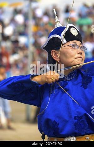 Ulaanbaatar, Mongolia, 11 giugno 2007: archer femminile in abiti tradizionali blu tirando indietro il cordone e concentrandosi al Naadam Festival ar Foto Stock