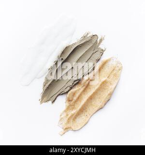 Concetto cosmetico sano con texture cosmetiche e diversi strisci di scrub corpo su tavola bianca. Scrub corpo di argilla, riso e mandorle Foto Stock