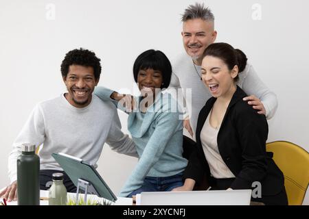 Diversi colleghi si riuniscono, ridono e si divertono mentre lavorano a un progetto Foto Stock