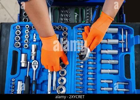 Meccanico automatico con chiave dinamometrica e diversi attrezzi presso l'officina di riparazione di automobili, vista dall'alto Foto Stock