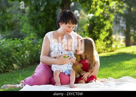 La madre e i suoi bambini all'aperto. Felice la mamma e i suoi bambini giocare nel parco insieme. Outdoor ritratto di famiglia felice Foto Stock