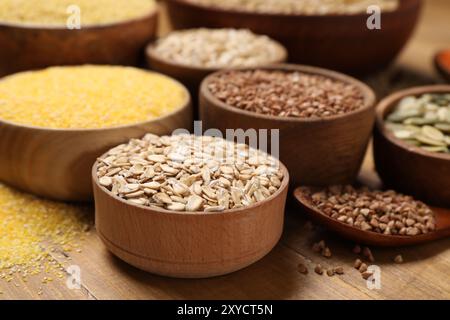 Diversi tipi di cereali e semi su tavola di legno, primo piano Foto Stock