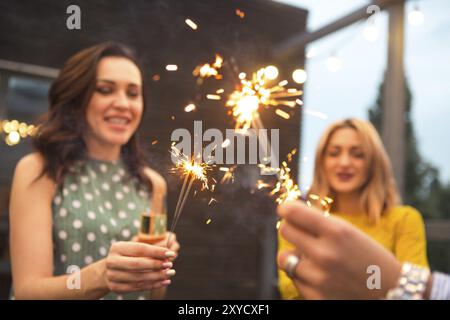 Un gruppo di ragazze che partying con flauti con vino frizzante e il Bengala fire divertirsi sulla parte Foto Stock