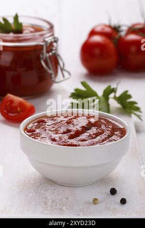 Salsa di pomodoro con prezzemolo all'aglio, pepe bianco e nero in un primo piano bianco. Verticale Foto Stock