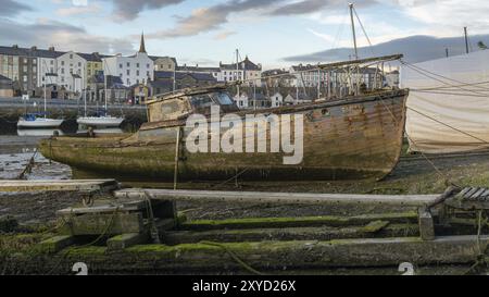 Caernarfon, Gwynedd, Galles, Regno Unito, 15 giugno, 2017: vecchia barca sporca sulla riva di Afon Seiont con nuove barche e alcune case sullo sfondo Foto Stock