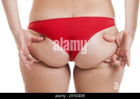 Donna in sovrappeso che tiene o pizzica il fondo del corpo grasso o le natiche vista posteriore bianca isolata Foto Stock