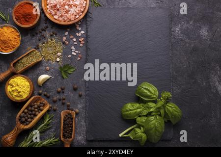 Spezie ed erbe su fondo di pietra nera. Vista dall'alto con spazio libero per menu o ricette Foto Stock