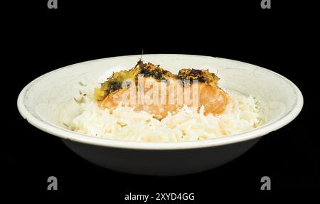 Delizioso pezzo di salmone su un letto di riso a grani lunghi, in un piatto profondo verso il nero Foto Stock