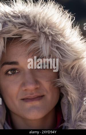 Primo piano Ritratto di donna con cappuccio in pelliccia invernale con uno sguardo caldo e intenso Foto Stock