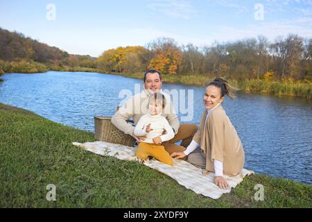 Giovane famiglia felice con piccolo figlio in appoggio sulla riva del lago Foto Stock